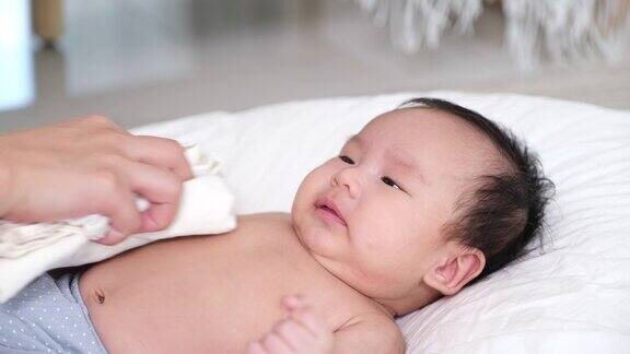 亚洲妇女母亲在家里客厅的床上用毛巾擦干她的女婴