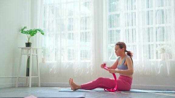 亚洲妇女在客厅训练普拉提或瑜伽为了健康和健康