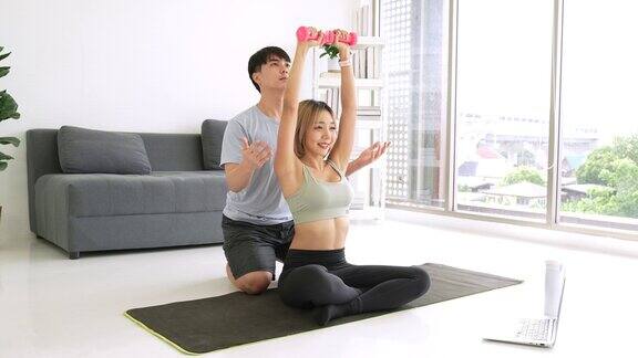 一对年轻的亚洲夫妇正在家里做健身训练
