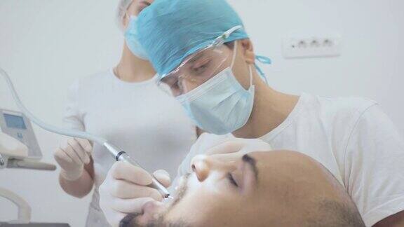 男牙医和牙科护士正在治疗一名男性病人