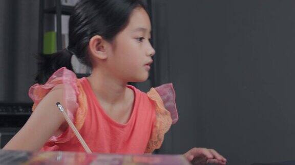 亚洲小女孩学习科学和在书上写笔记而呆在家里自主学习在线学习她正在用铅笔写家庭作业