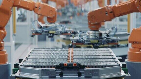 橙色机械臂的自动化生产线特写用于汽车工业装配的电动汽车电池组延时拍摄电动汽车智能工厂配备机械臂的生产线