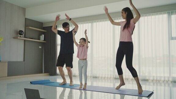 亚洲年轻的家庭训练在家里的客厅