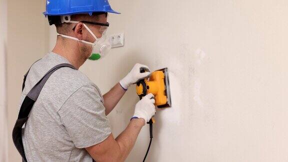 工人带着呼吸器擦拭墙上的灰泥