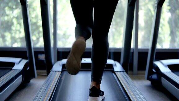 健身女孩在健身俱乐部的跑步机上快速奔跑金发女孩穿着运动服在健身健康生活理念体育活动