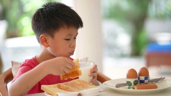 亚洲小孩早餐喝一杯牛奶健康早餐