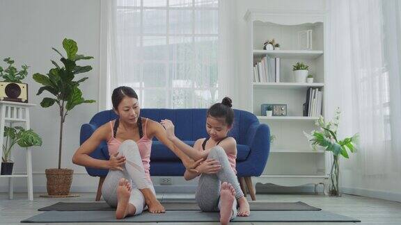 母女俩在家里练习瑜伽坐姿脊柱扭转式或坐式