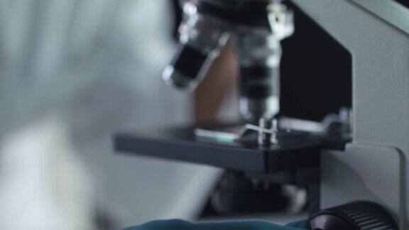 女科学家在分析样品时调整显微镜上的焦点