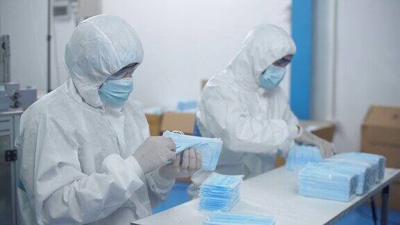 A口罩厂生产线上两名技术人员检查防护口罩机进度