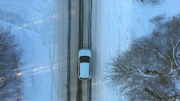 白色汽车通过白雪覆盖的森林道路的特写冬日里SUV行驶在美丽的乡间小路上寒假旅行在自然家庭旅行航拍俯视图