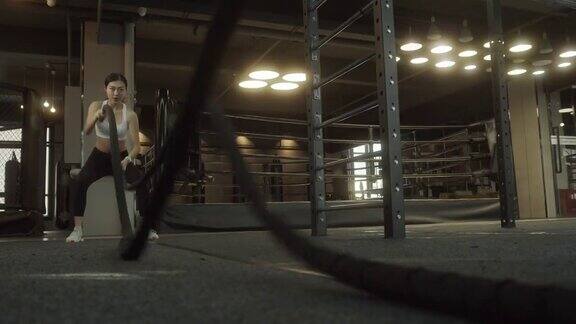 女子训练做格斗绳锻炼锻炼手臂和有氧运动的健身房锻炼健身人士在健身房用格斗绳练习