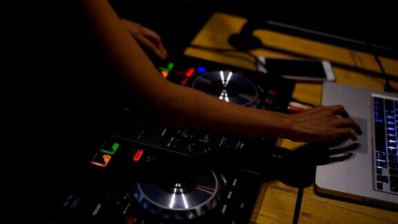 特写镜头双手的DJ甲板转盘混音控制台在迪斯科派对夜总会为庆祝活动