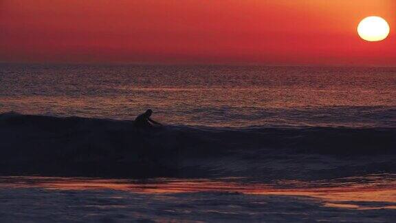 慢镜头:太阳落在一个冲浪者的身后他在海上乘风而上冲浪的一生
