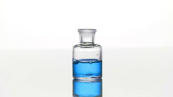 蓝色的艾菊油与蓝色的液体落入透明的瓶子
