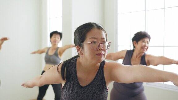 一群亚洲女性在健身房与家人一起锻炼、练习瑜伽