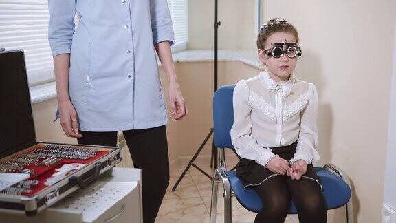 孩子坐在眼科医生的椅子上用特制的眼镜检查视力