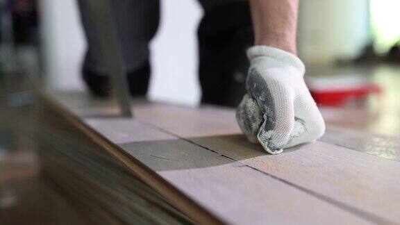 戴着防护手套的工人用锯子切割镶木地板