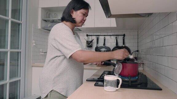 亚洲妇女在厨房做饭同时看手机的食谱