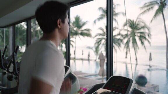 一名亚洲男子早上在度假健身中心的跑步机上锻炼
