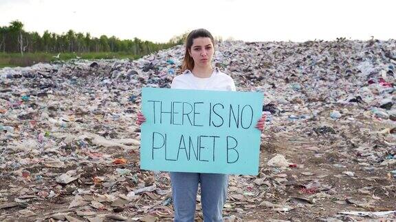 生态活动家们举着“没有B星球”的海报站在垃圾填埋场旁边的女人或女孩女学生在看镜头