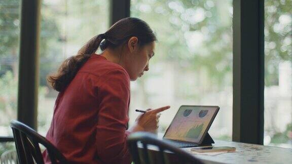 一名女子在咖啡店用平板电脑工作