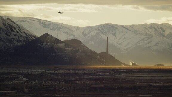 在一个多云的日子里一架商用飞机的剪影飞过盐湖城犹他州和雪山的冬季日落