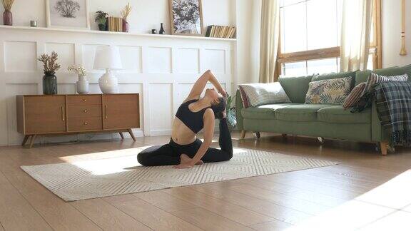 运动印度女人做伸展运动瑜伽黑色运动服灯光房间在家里早上