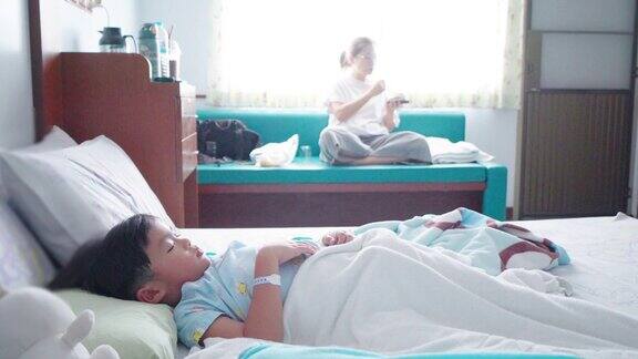 一位亚洲母亲在医院的病床上照顾生病的儿子