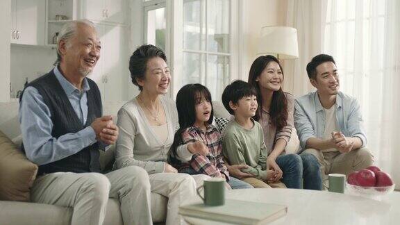 三代亚洲家庭在家里看电视