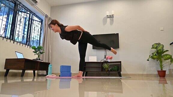 有吸引力的年轻亚洲女人锻炼和做瑜伽的位置而休息在家里