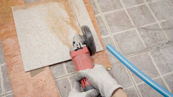 近距离使用圆锯机刀片切割瓷砖地板的人的手并使用水来防止切割引起的灰尘分散