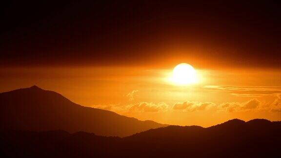 橘红色的太阳从云层中钻出来向地平线移动
