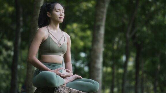 周末亚裔华裔妇女在公园里冥想练习瑜伽