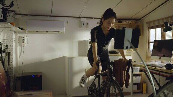 亚洲女性自行车手她正在家里锻炼她骑着模拟自行车