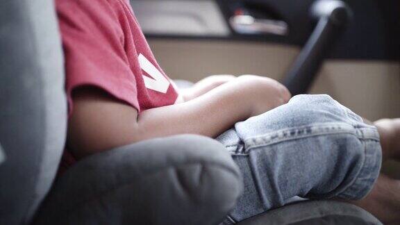 小男孩在路上坐在汽车安全座椅上看智能手机