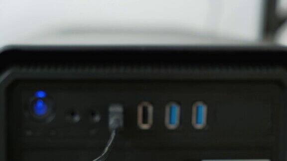 前面的特写镜头显示USB电缆插入端口连接数据到黑色桌面电脑在白色背景在侧面有电源按钮和扬声器插孔连接器