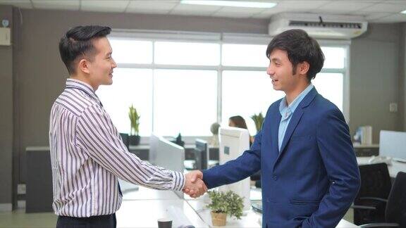 在办公室里一位亚洲商人在握手谈判完成后合作协议就成功了