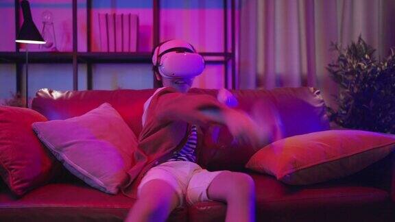 亚洲儿童男孩戴着VR或虚拟现实眼镜头戴耳机站在家里客厅的电视机前玩电子游戏在隔离期的技术和创新概念霓虹灯夜的生活方式