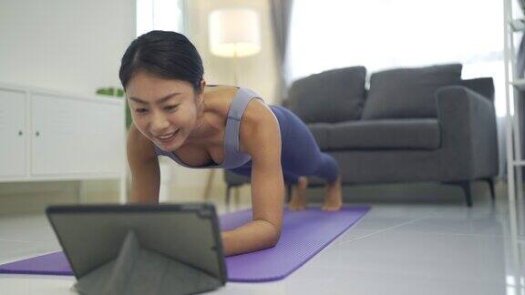 4K年轻女子在家使用数字平板电脑在线教瑜伽