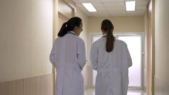 两名亚裔女医生在医院走廊随意走动和交谈