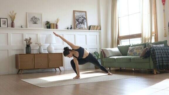 一个年轻的印度女人在早上她做伸展运动做运动瑜伽黑色运动服打底裤和上衣一个明亮的房间在家里