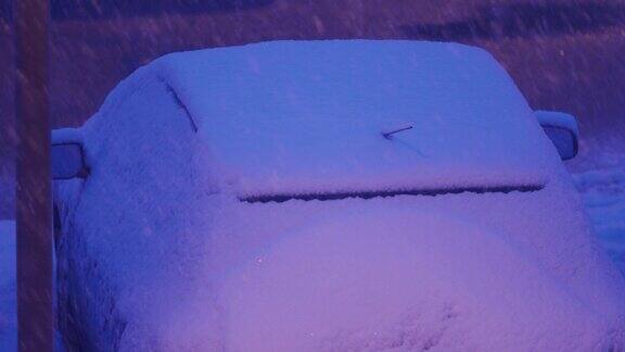 在冬天黄昏时分停在停车场路灯下的汽车被雪覆盖城市街道上大雪纷飞