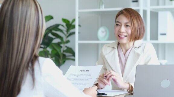 年轻的亚洲女性申请人在办公室给面试官她的简历工作面试求职商业概念