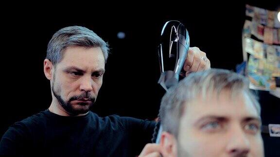 野蛮的男性理发师干头发和梳头发给客户肖像的观点