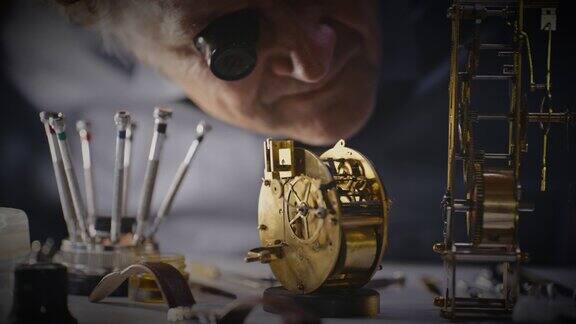 男钟表匠用放大镜检查铜钟
