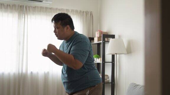年轻的亚洲男人正在家里的客厅里节食打拳击