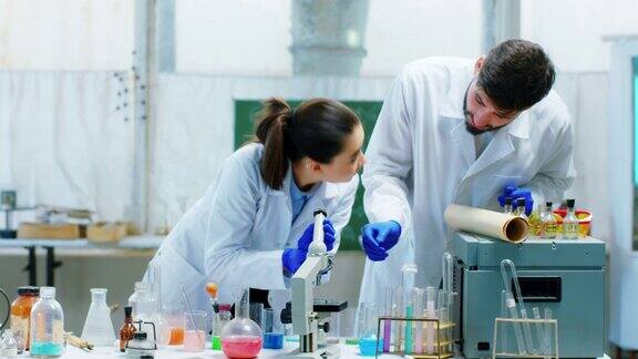 科学家男女通过显微镜与同事一起讨论在化学实验室中科学实验工业