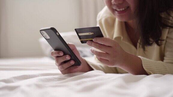 女子躺在床上用信用卡和智能手机在移动应用程序上在线支付