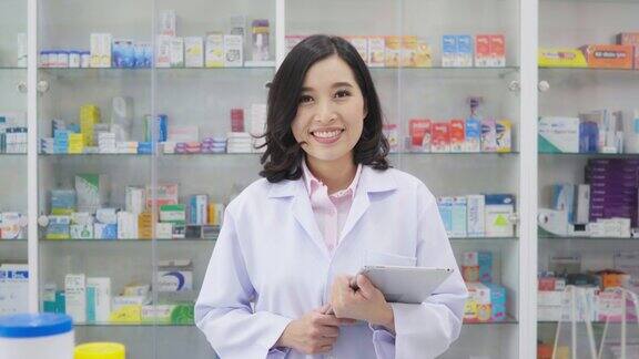 在药店背景中使用药片的亚洲药剂师的英雄肖像医疗保健和医疗概念