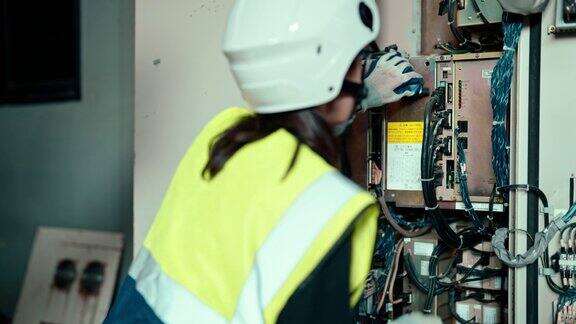 高加索电气工程师检查机械臂控制柜接线以修复电气故障的后视图